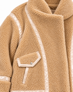 Close-up of the jacket’s plush tan sherpa texture and contrast lace-style trim along a pocket
