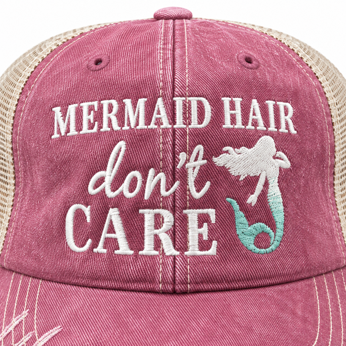 Close-up of white embroidered Mermaid Hair Don't Care lettering with teal mermaid tail accent on washed pink distressed trucker hat front panel

