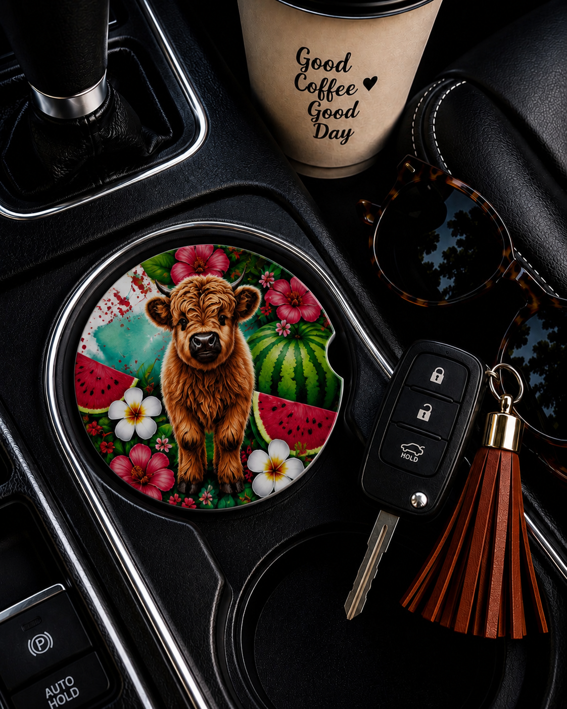 Highland Cow Watermelon ceramic car coaster in cup holder — fluffy Highland cow calf with watermelon slices and tropical flowers, shown in car console with coffee cup and keys
