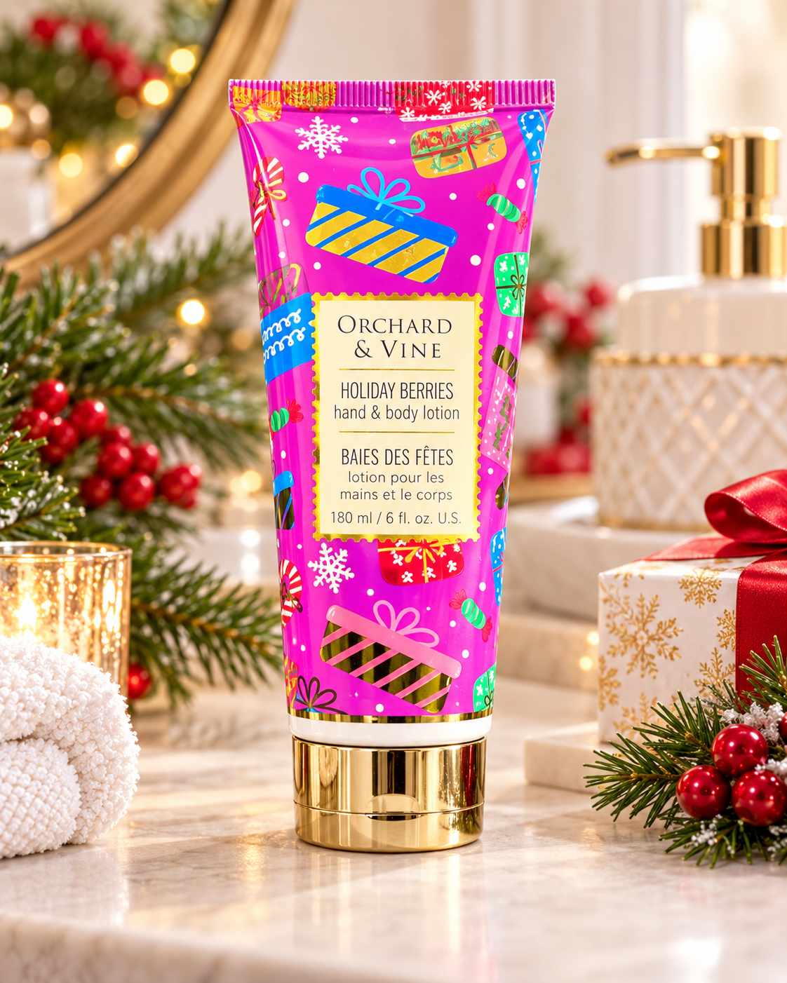Holiday Berries hand and body lotion in a pink Christmas tube, displayed beside a towel, candle, wrapped gift, and winter greenery
