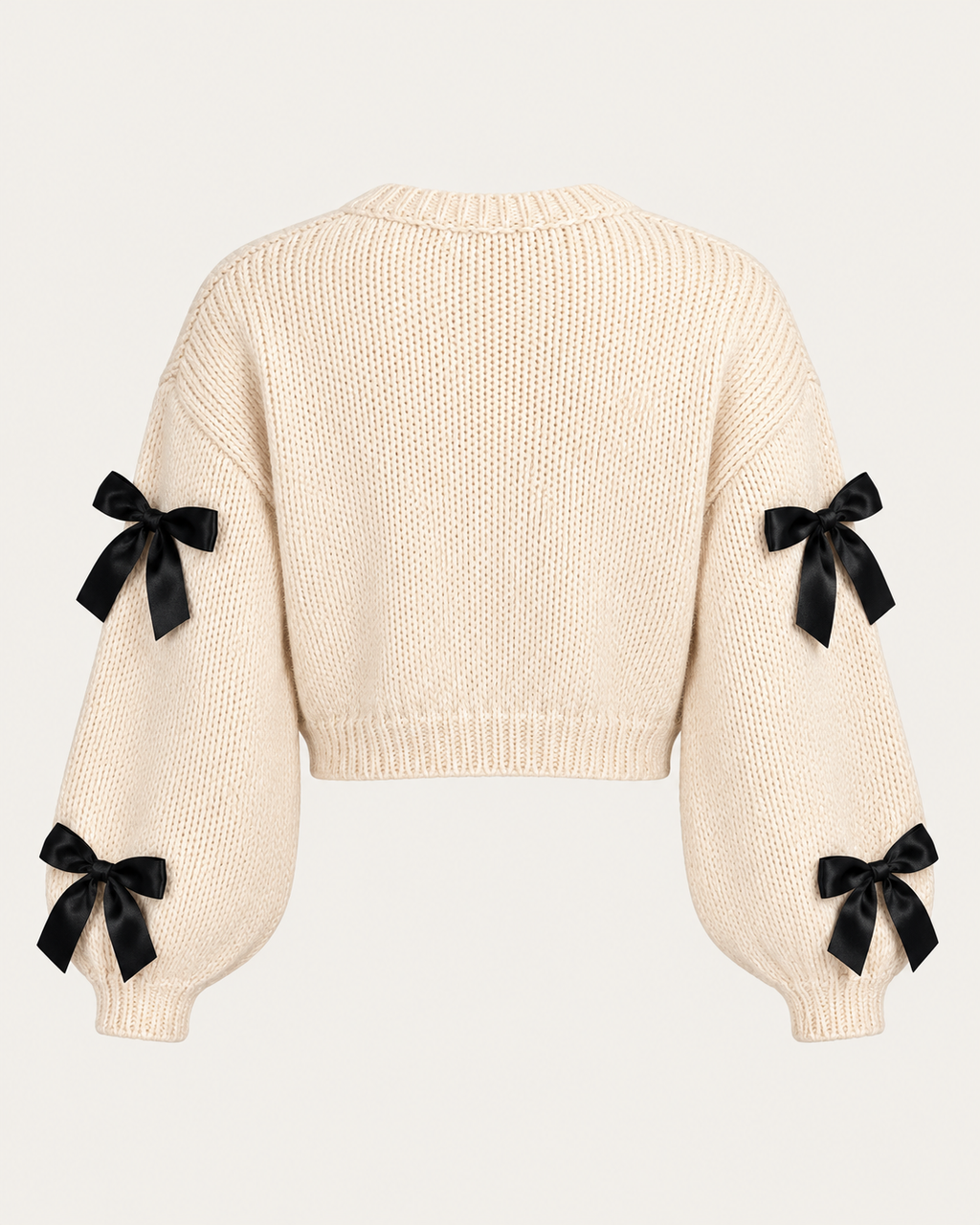 Back view of the tan cropped cardigan showing the plain knit back, black bows on the sleeves, and ribbed cuffs and hem
