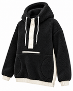 Angled view of the black sherpa hoodie showing the hood, snap neckline, front pockets, and contrasting ivory side panel

