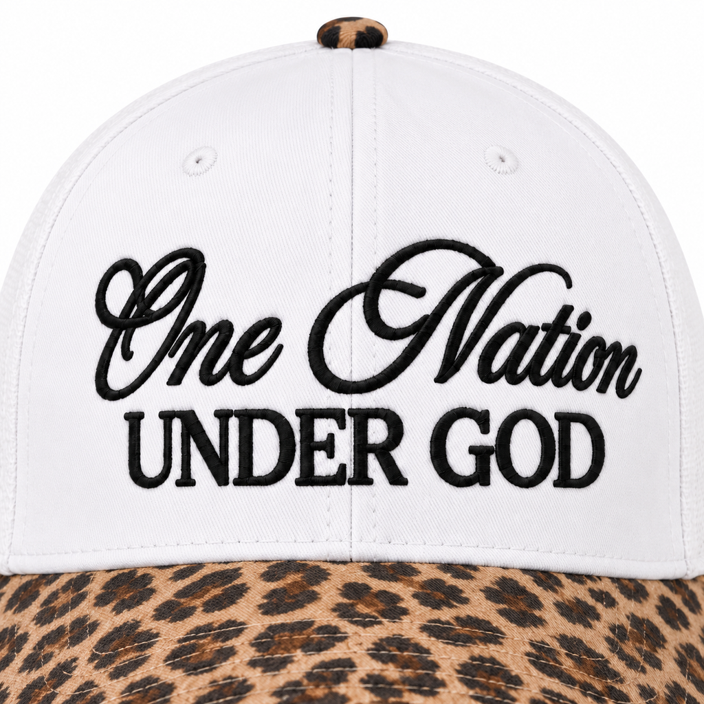 Close-up of One Nation Under God Baseball Cap in Leopard showing bold black embroidered script reading One Nation in cursive and Under God in block lettering on white structured cotton crown with tan and black leopard print bill at bottom edge and leopard print top button

