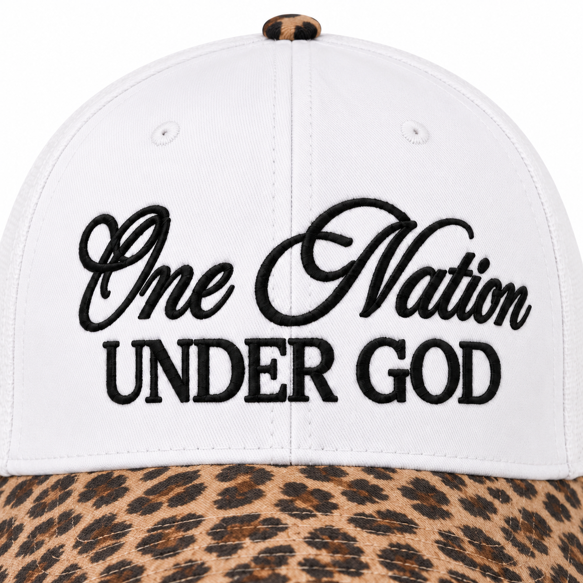 Close-up of One Nation Under God Baseball Cap in Leopard showing bold black embroidered script reading One Nation in cursive and Under God in block lettering on white structured cotton crown with tan and black leopard print bill at bottom edge and leopard print top button
