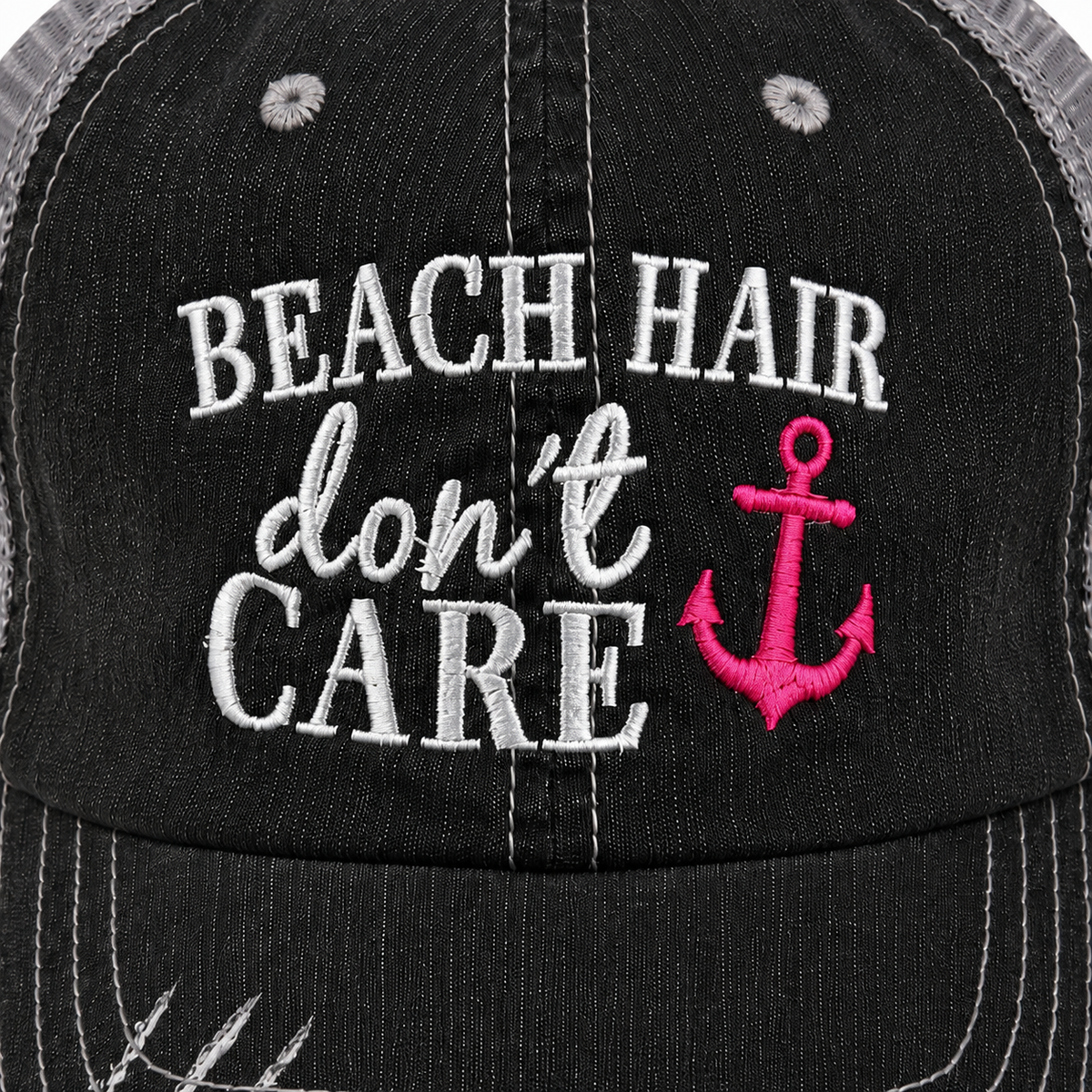 Close-up of Beach Hair Don’t Care trucker hat showing raised white embroidery and bright pink anchor on the distressed black front