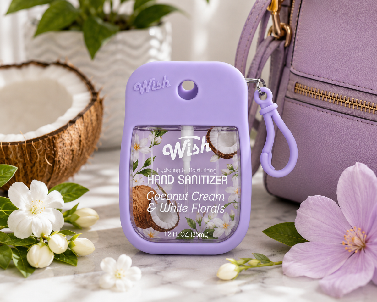 A lavender purple Wish brand hand sanitizer bottle with a matching carabiner clip, styled on a marble surface with a purple handbag, white flowers, and a coconut half in the background.