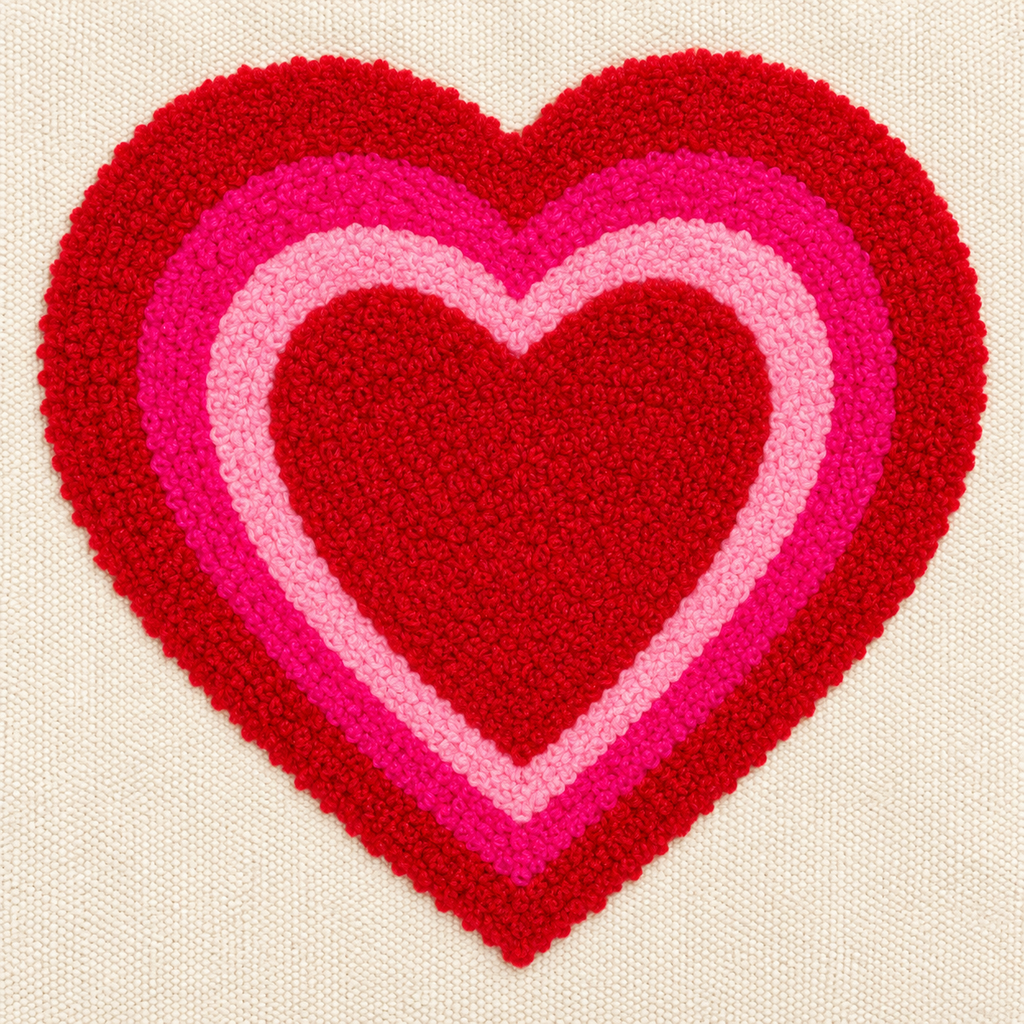 Close-up of large textured punch needle layered heart design in red outer ring, hot pink middle ring, and light pink inner ring on natural canvas tote bag
