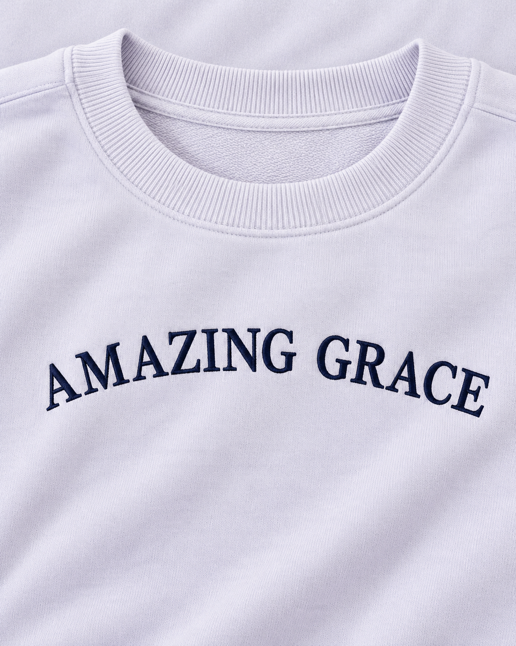 Close-up of navy Amazing Grace lettering and the ribbed crew neckline on the light lavender sweatshirt
