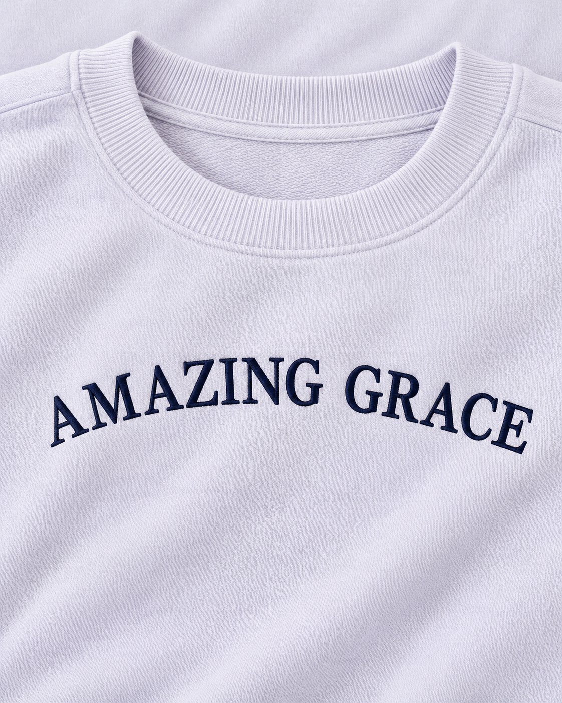 Close-up of navy Amazing Grace lettering and the ribbed crew neckline on the light lavender sweatshirt
