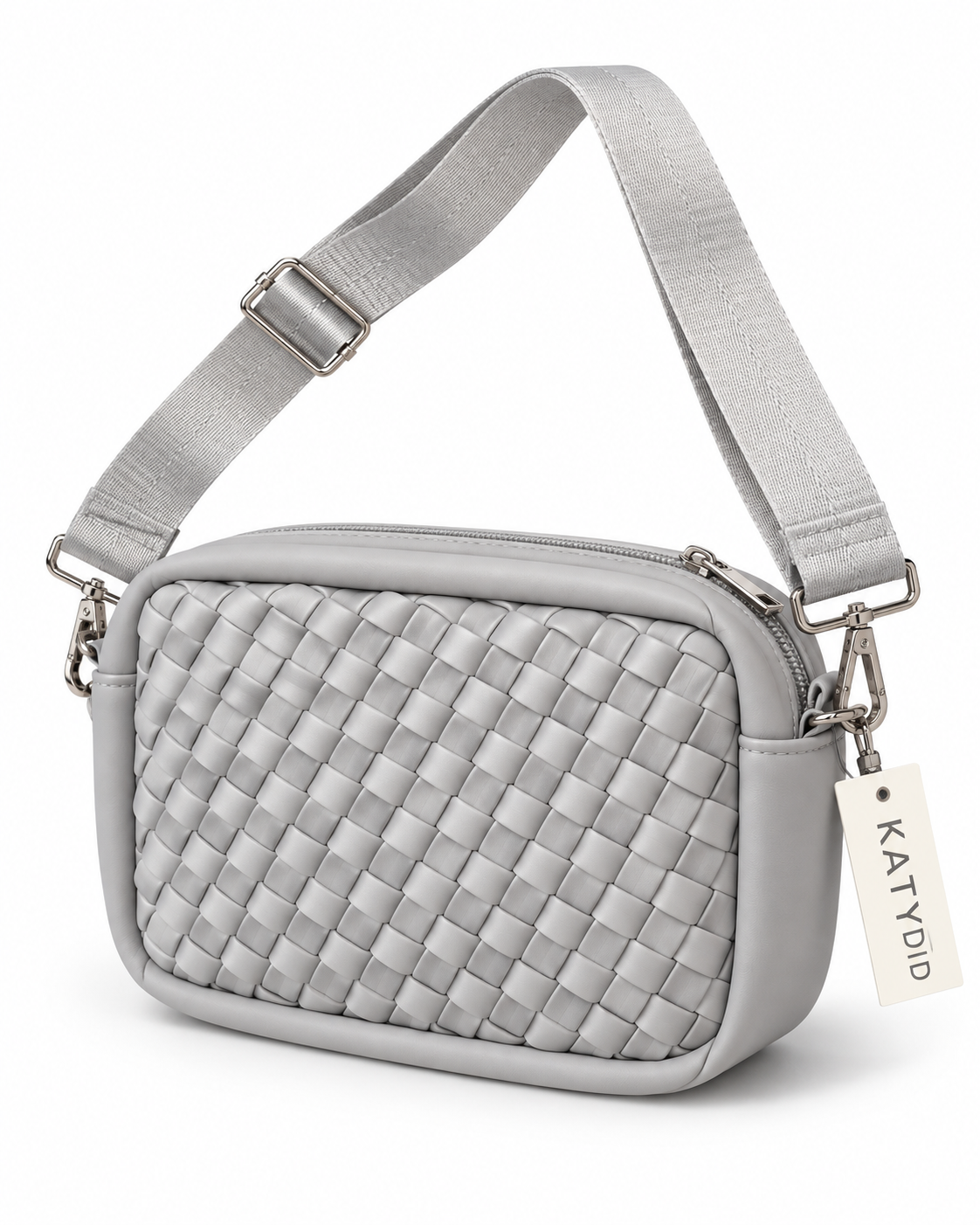 Gray Woven Crossbody Bag three-quarter angle view showing light gray interlaced woven panel, smooth gray trim, top zipper closure with silver pull, adjustable wide gray webbing strap with silver swivel clips, and Katydid hang tag on white background
