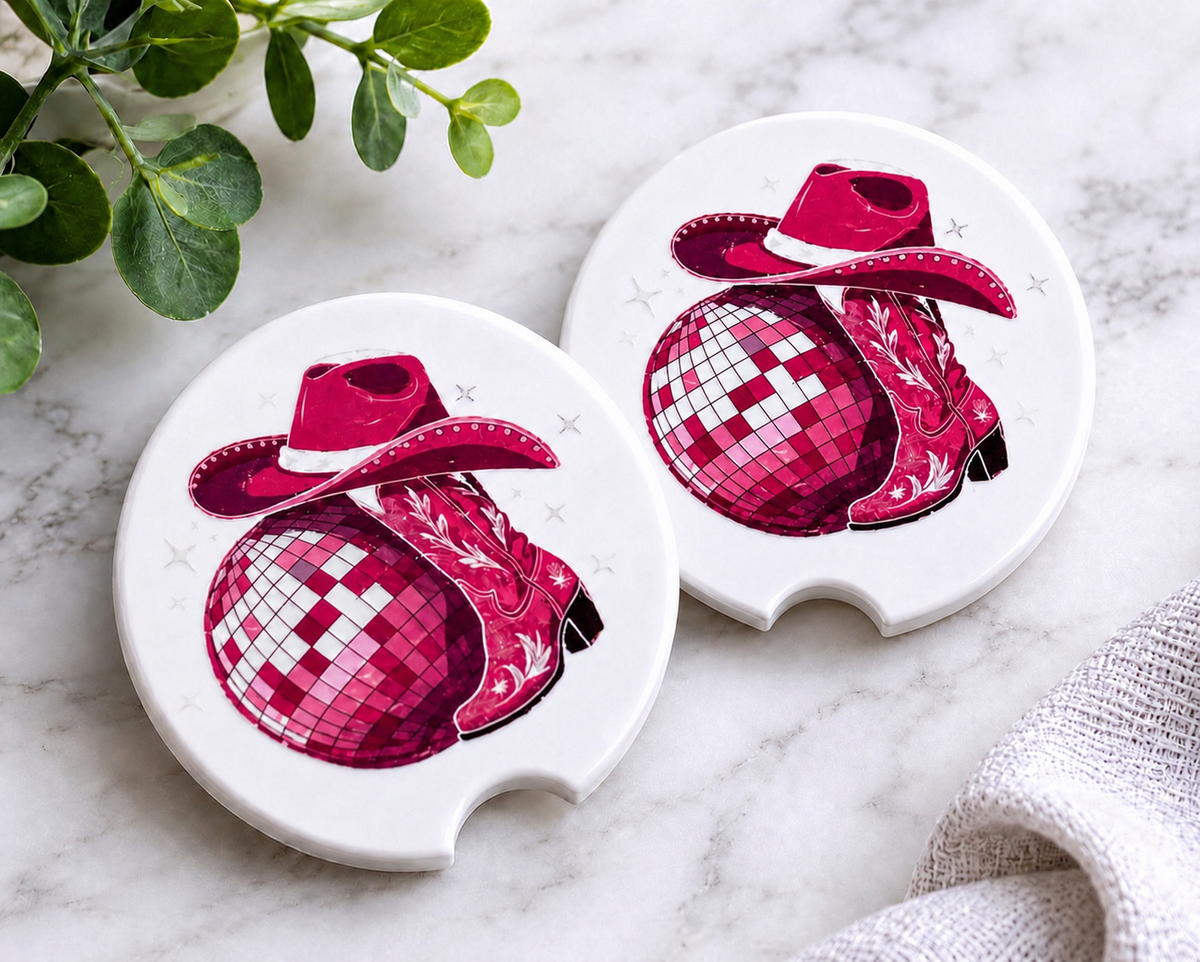 Disco Cowgirl Car Coaster Set — set of 2 ceramic coasters with pink disco ball, cowboy hat, and cowgirl boots design with sparkle accents on white background, on marble surface
