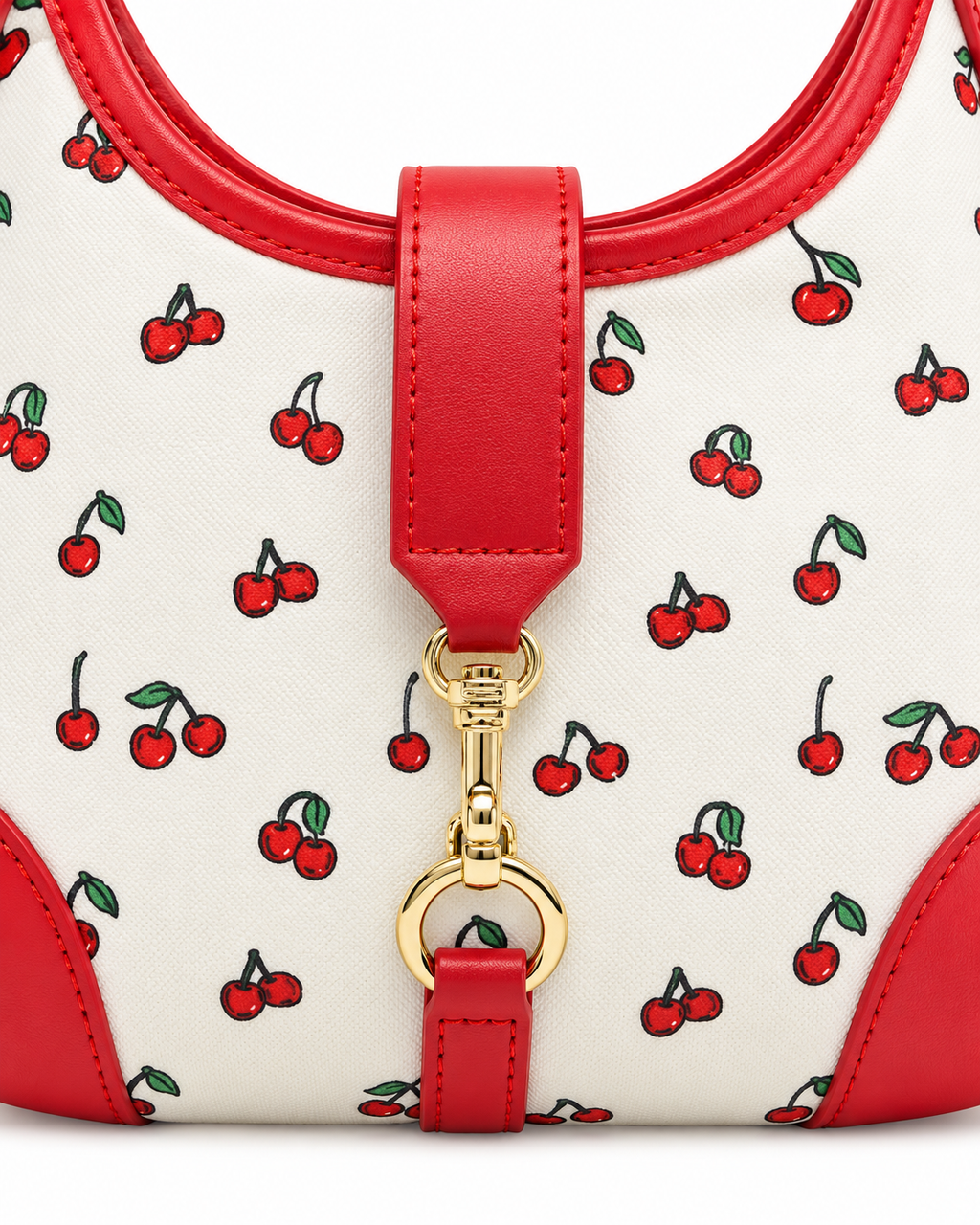 Close-up of Cherry Pattern Hamptons Hobo Bag showing gold horsebit snaffle clasp on center red faux leather strap tab, coated cream canvas with allover red cherry print and green stems, and red faux leather top trim with stitched edge detail
