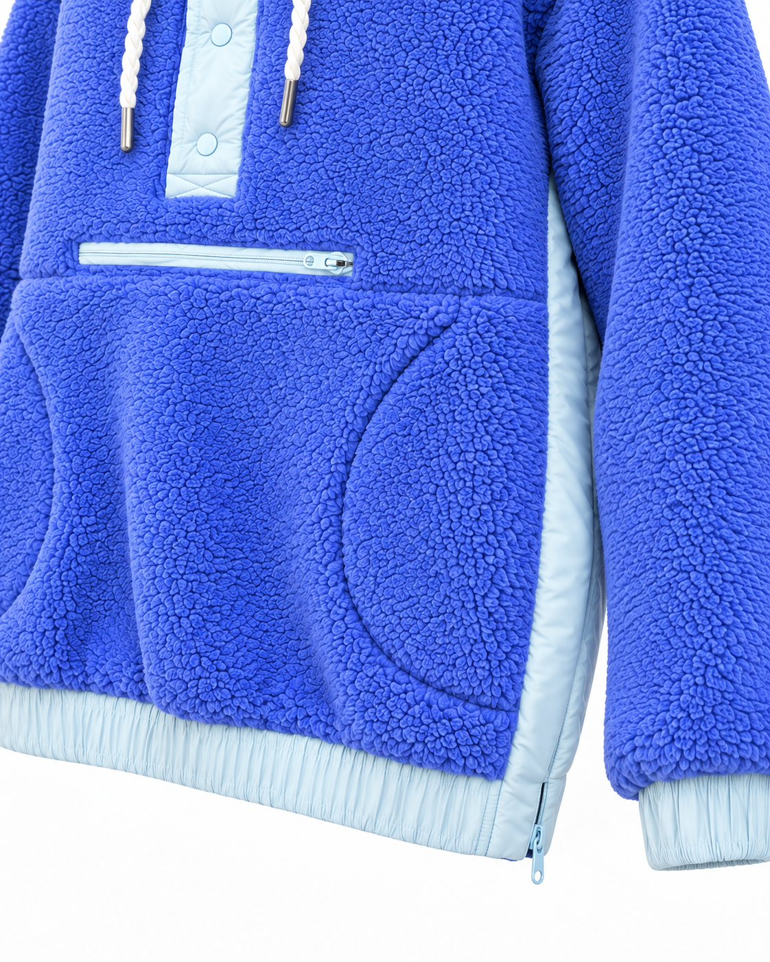 Close-up of the blue sherpa hoodie showing the front zippered pocket, curved hand-pocket opening, light blue side panel, and side-hem zipper
