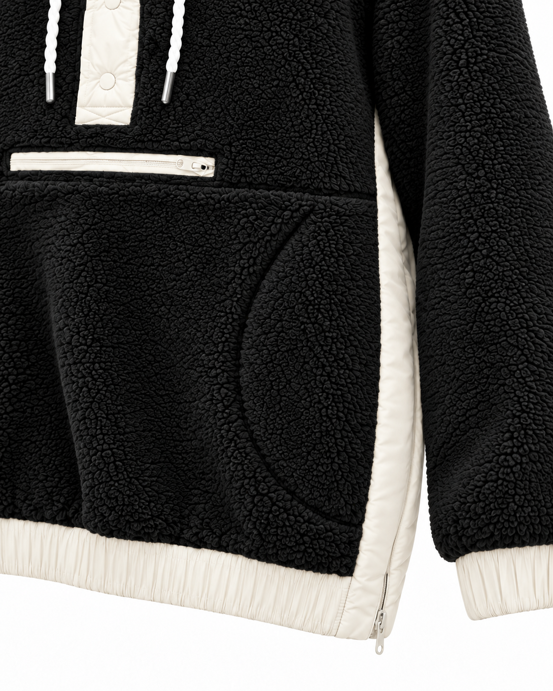 Close-up of the black sherpa hoodie showing the front zippered pocket, curved hand-pocket opening, ivory side panel, and contrasting cuff and hem
