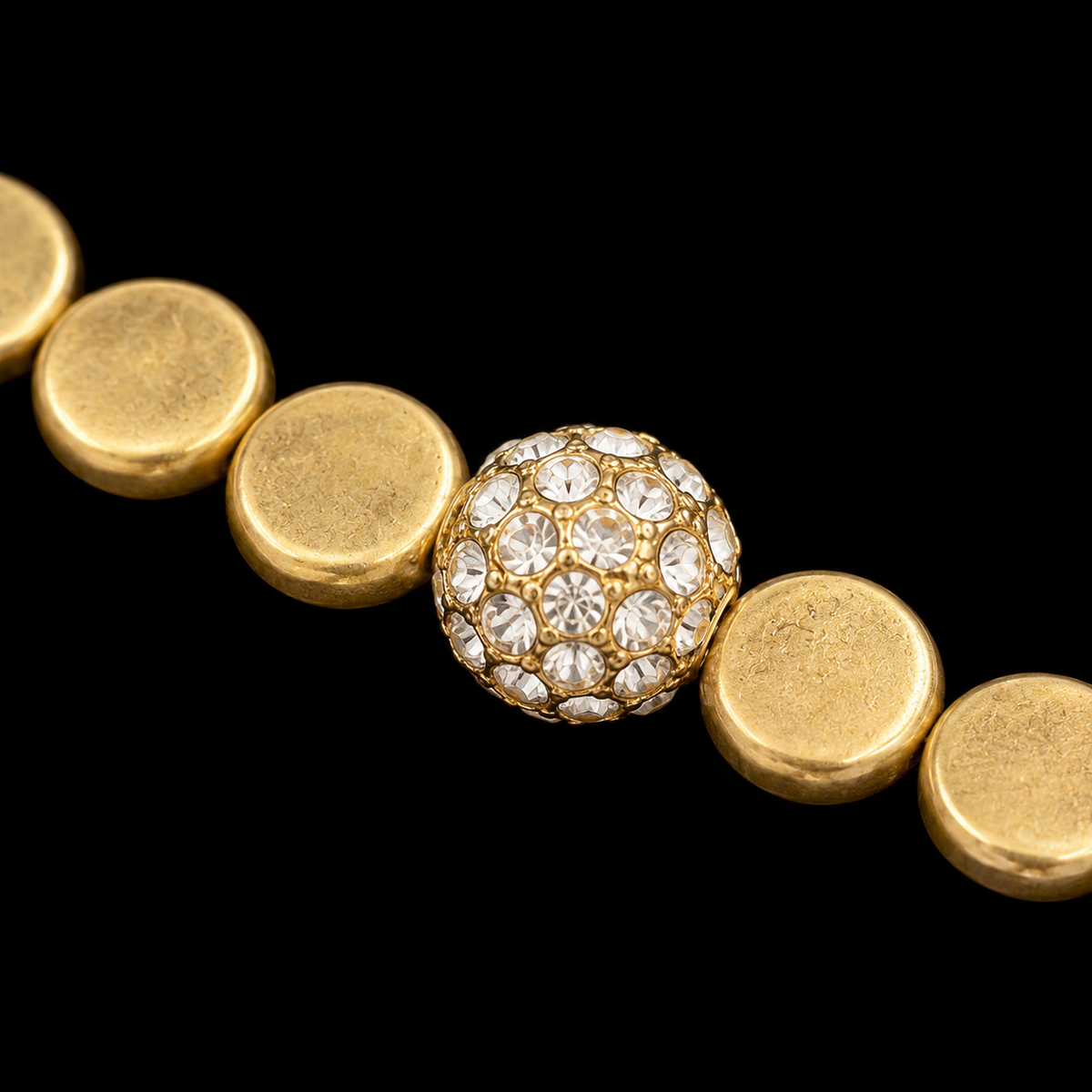 Close-up of pavé crystal ball accent bead surrounded by brushed gold coin beads on stretch bracelet
