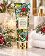 Winter Frost hand and body lotion in a green holiday tube with a gold-tone cap, displayed beside towels, candles, and winter greenery
