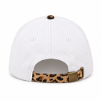 Back view of One Nation Under God Baseball Cap in Leopard showing white solid back panels with white ventilation eyelets, leopard print top button, and tan and black leopard print adjustable strap with gold metal slide buckle closure on white background
