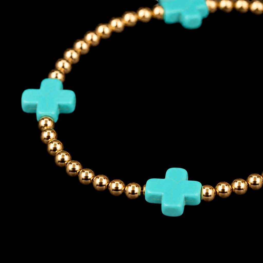 Close-up of polished gold-tone ball beads and turquoise cross accent bead on stretch bracelet
