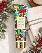 Winter Frost hand and body lotion laid flat beside a striped towel, frosted greenery, and red berries
