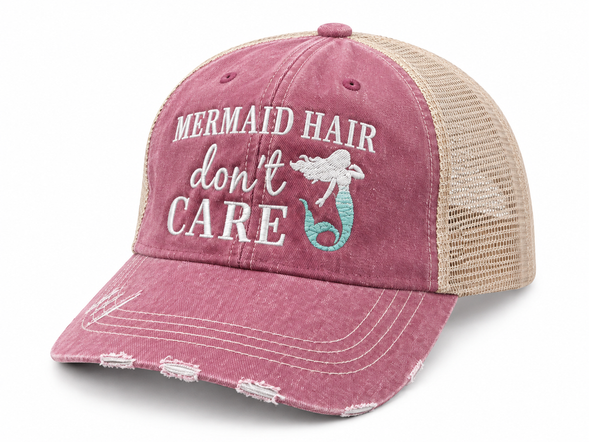 Mermaid Hair Don't Care Trucker Hat three-quarter angle view showing washed pink distressed front, tan mesh back, and white and teal mermaid embroidery on white background
