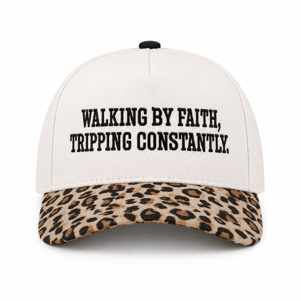 Walking By Faith Tripping Constantly Baseball Cap in Leopard front view showing cream structured cotton crown with black embroidered Walking By Faith Tripping Constantly block lettering, tan and brown leopard print bill, and black top button on white background
