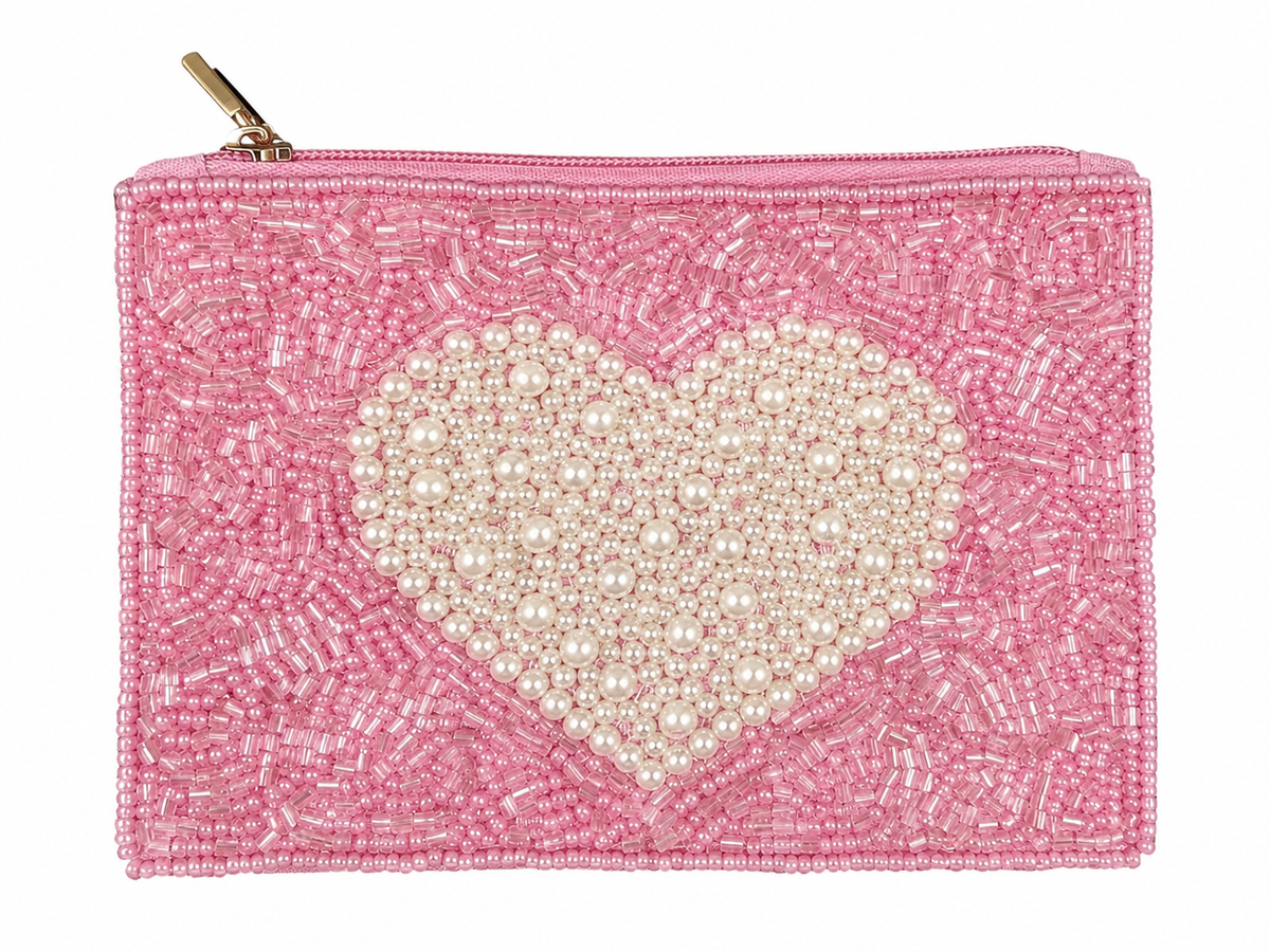 A pink beaded clutch bag featuring a large heart-shaped embellishment made of cream faux pearls in the center, with a gold zipper pull at the top, shown against a plain white background.