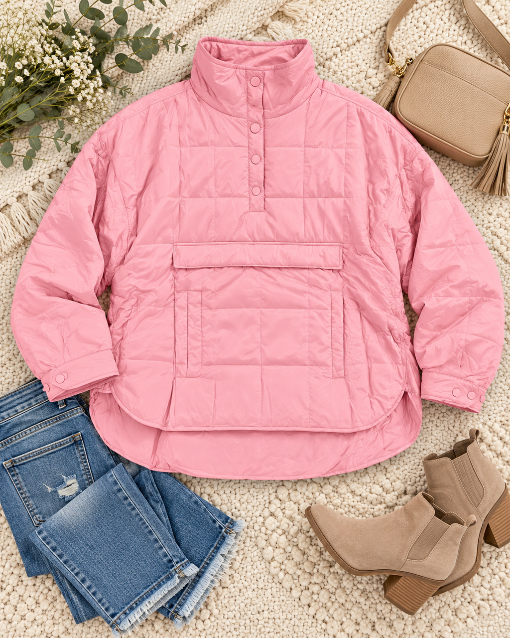 Pink Quilted Puffer Pullover Jacket styled in flat lay on cream chunky knit rug with distressed blue jeans, tan suede block-heel Chelsea ankle boots, tan square camera crossbody bag with gold tassel zipper, eucalyptus, and baby's breath
