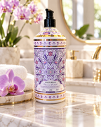 Florence Orchid body wash styled on a marble bathroom counter with purple orchids, white towels, and gold fixtures
