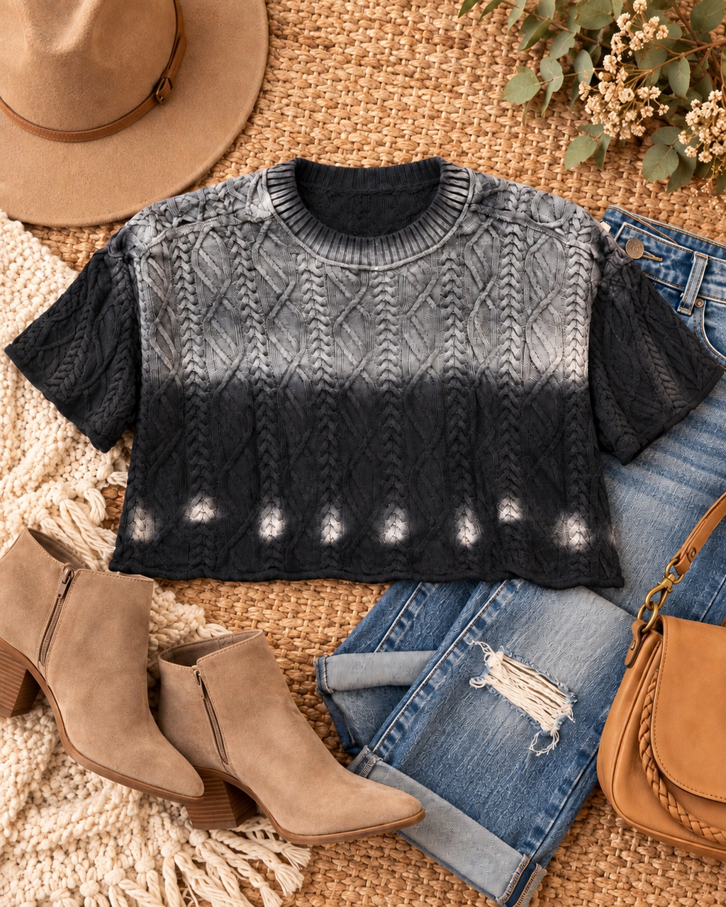 Black ombre cable knit cropped sweater styled in a flat lay with distressed jeans, tan ankle boots, brown bag, and camel hat
