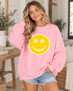 Model wearing the light pink Daisy Eyes sweatshirt with a yellow smiley face and white flower eyes, paired with denim shorts
