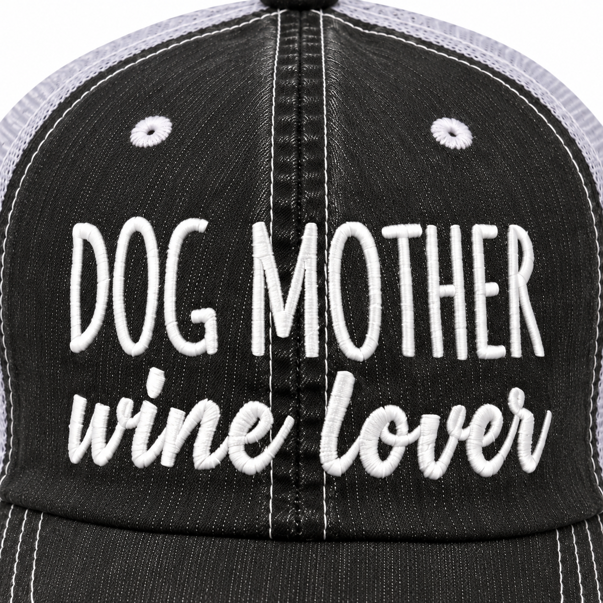 Close-up of white embroidered Dog Mother block lettering and wine lover script on distressed black trucker hat front panel
