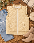 Beige quilted ruffle-trim vest styled on light-wash jeans
