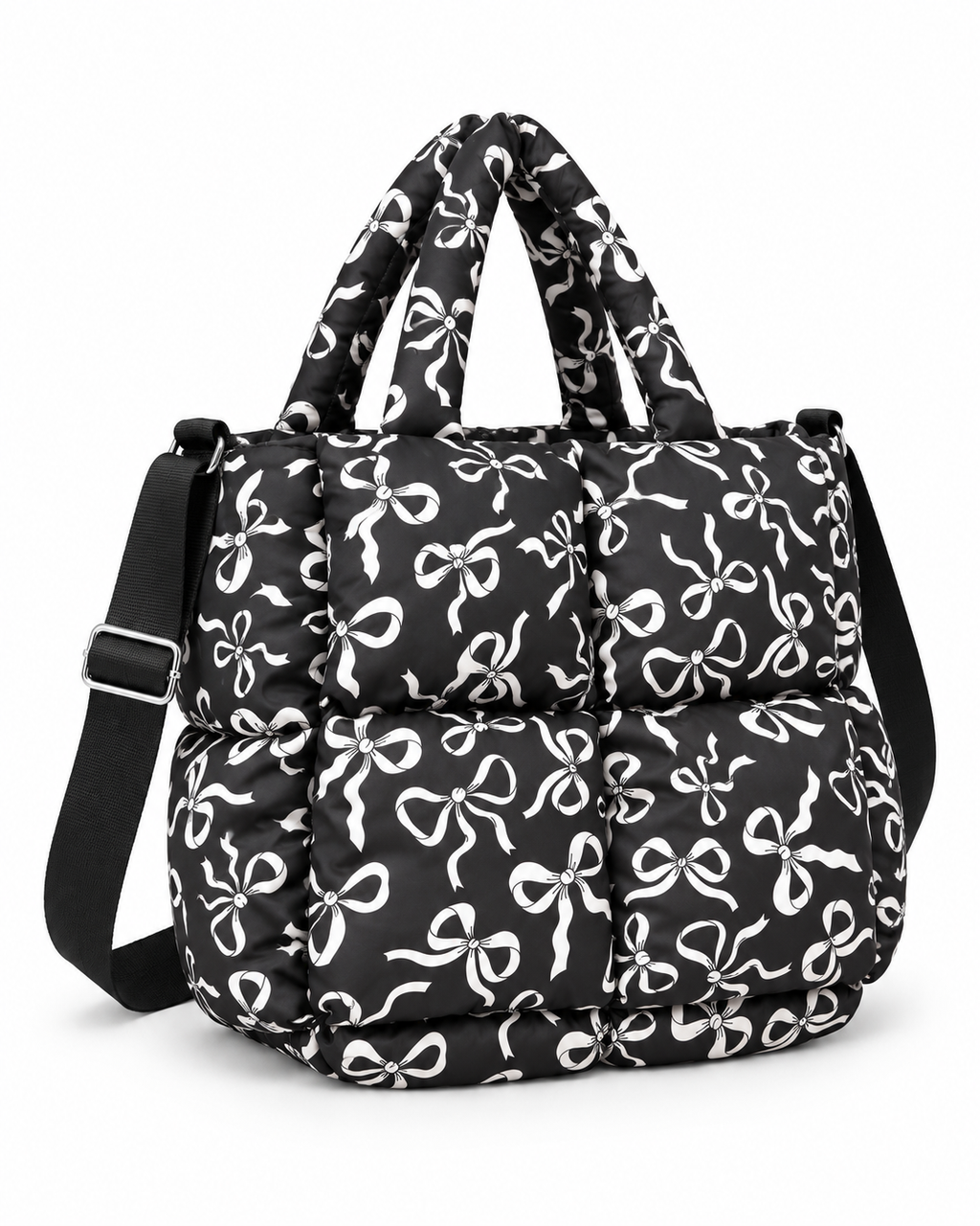 Black Bow Print Puffer Tote three-quarter angle view showing black puffer body with all-over white bow print, dual padded top handles, adjustable black shoulder strap, and silver hardware on white background
