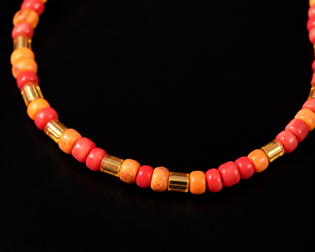 Close-up of coral pink and orange round seed beads alternating with gold-tone bugle beads on stretch bracelet
