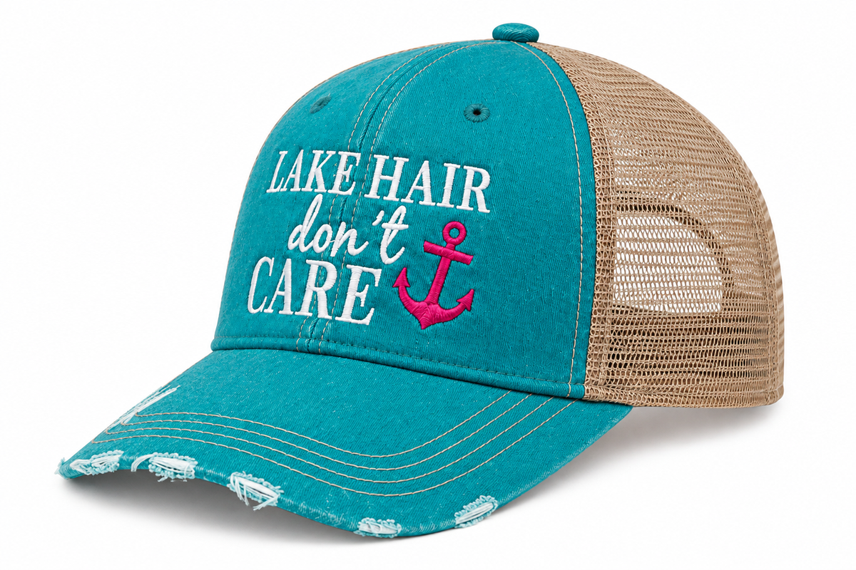 Side view distressed trucker hat with a teal front panel and brim, tan mesh back, and white embroidered text reading 'LAKE HAIR don't CARE' alongside a pink anchor graphic.
