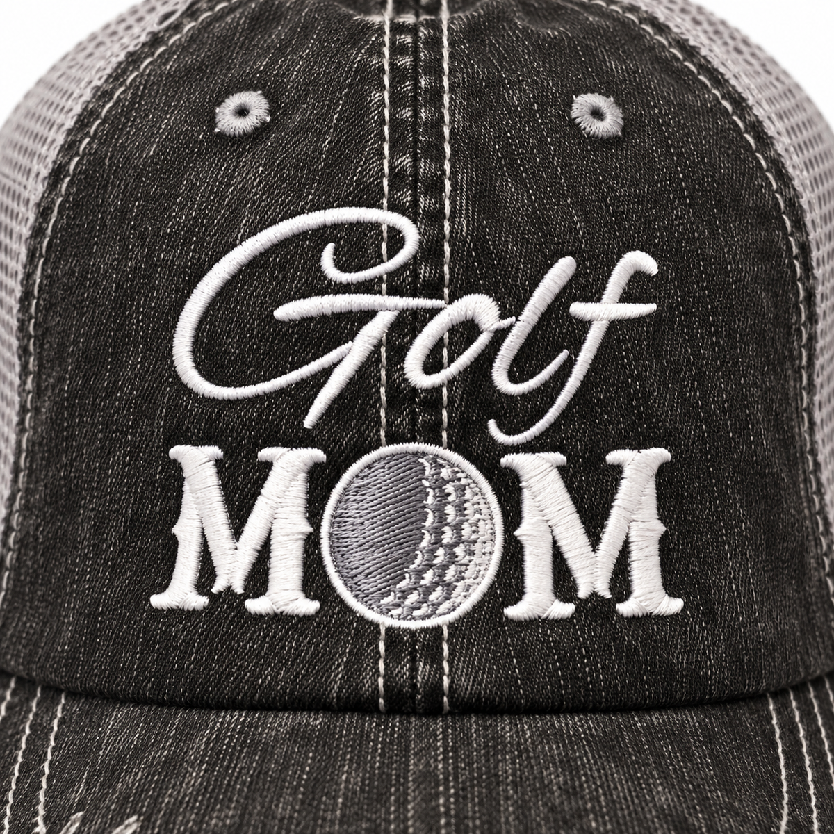 Close-up of white embroidered Golf script and Mom block lettering with gray embroidered golf ball detail replacing the letter O on distressed black trucker hat front panel
