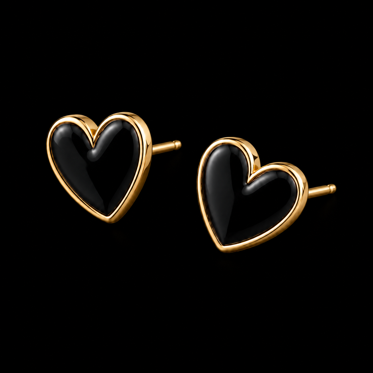 Black enamel heart stud earrings with gold-tone trim shown at an angle with gold post backings visible on black background
