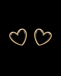 Black enamel heart stud earrings with polished gold-tone bezel trim shown as a pair front-facing on black background
