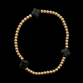 Gold beaded stretch bracelet with three black clover accents displayed flat in a circle on black background
