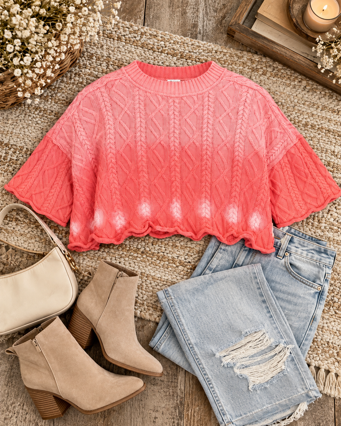 Pink cropped sweater styled flat with light-wash jeans and brown boots
