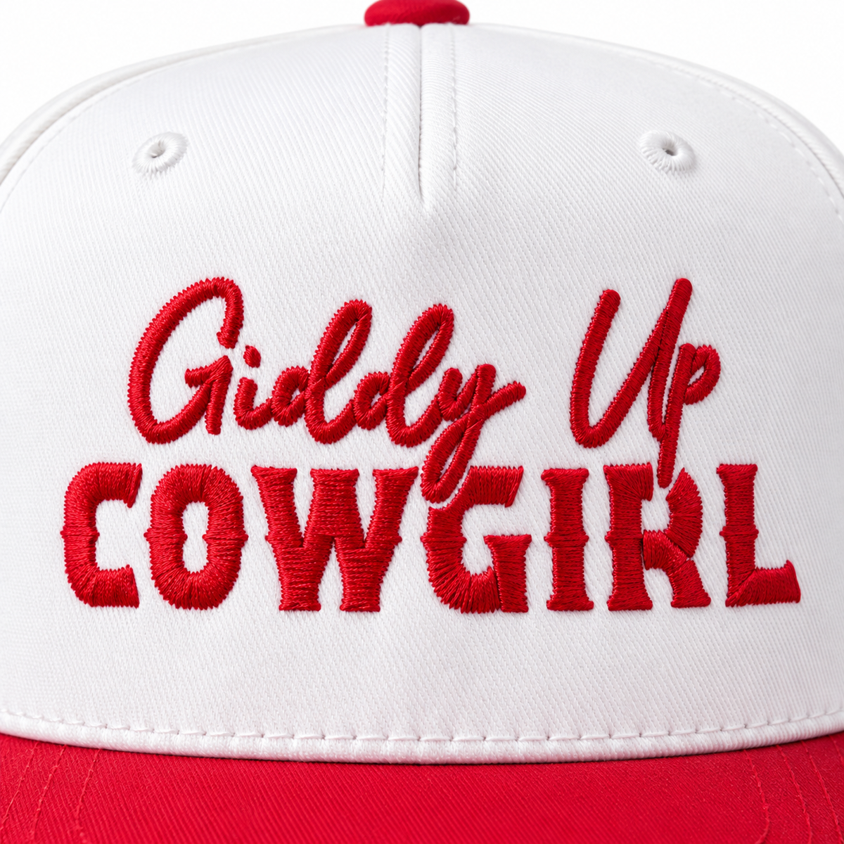 Close-up of red embroidered Giddy Up Cowgirl lettering in script and block lettering on white structured front panel of baseball cap
