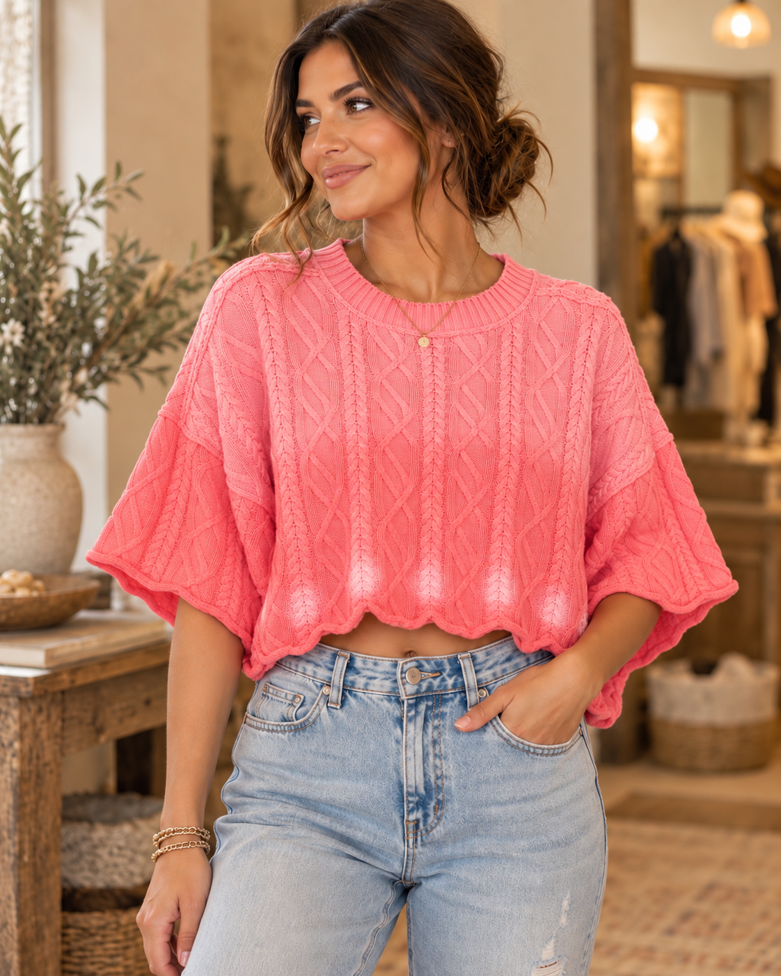 Model wearing a bright pink cropped cable-knit sweater with short sleeves and white dot details near the hem
