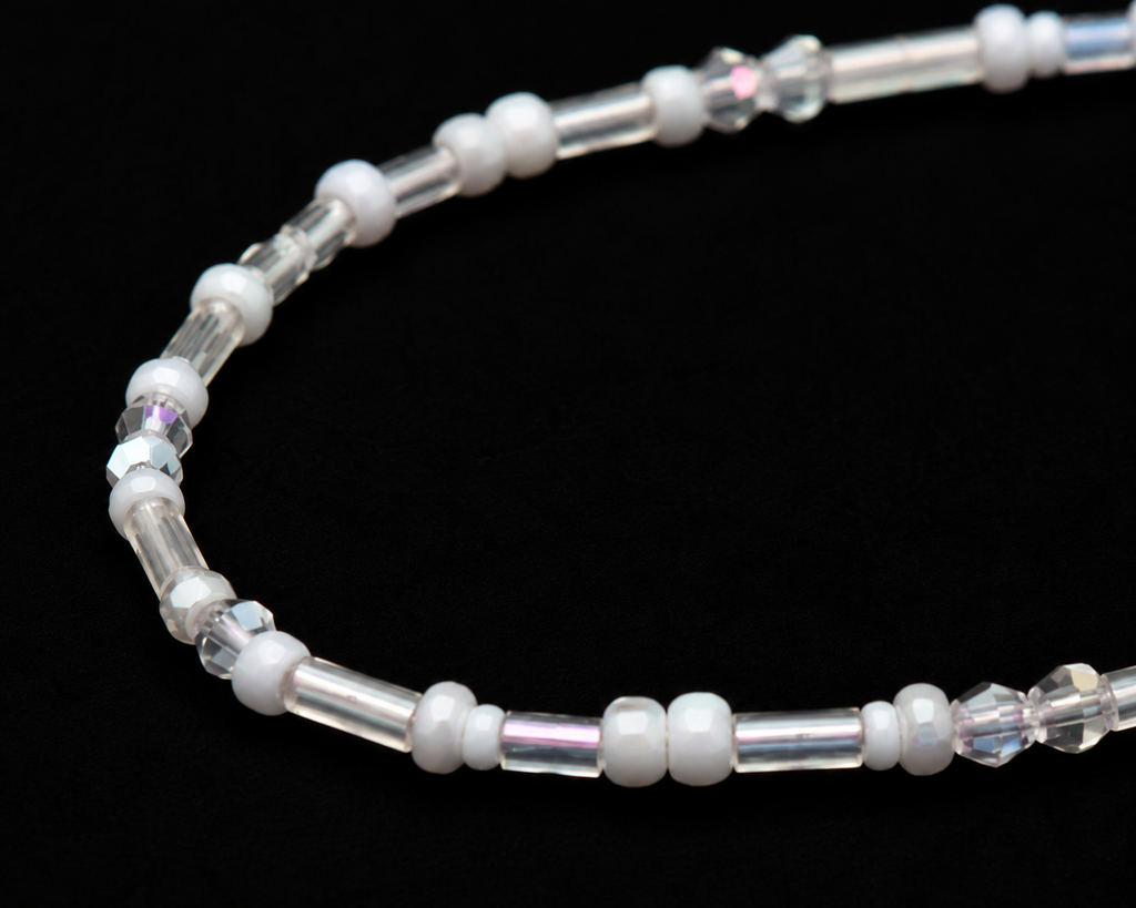 Close-up of white round seed beads, clear bugle beads, and iridescent crystal rondelle beads on delicate stretch bracelet
