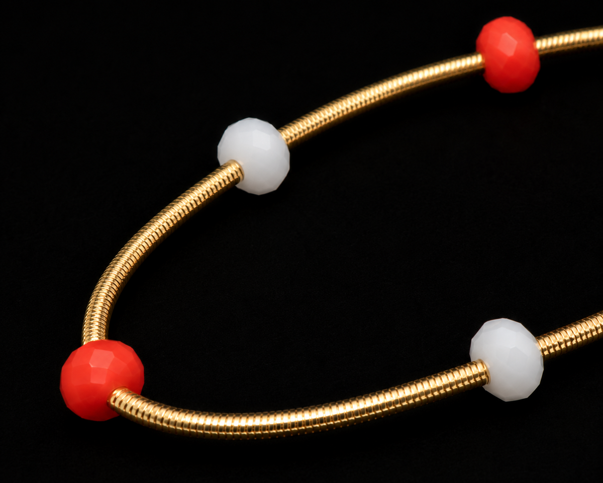 Close-up of red and white faceted rondelle beads threaded on gold snake coil stretch bracelet
