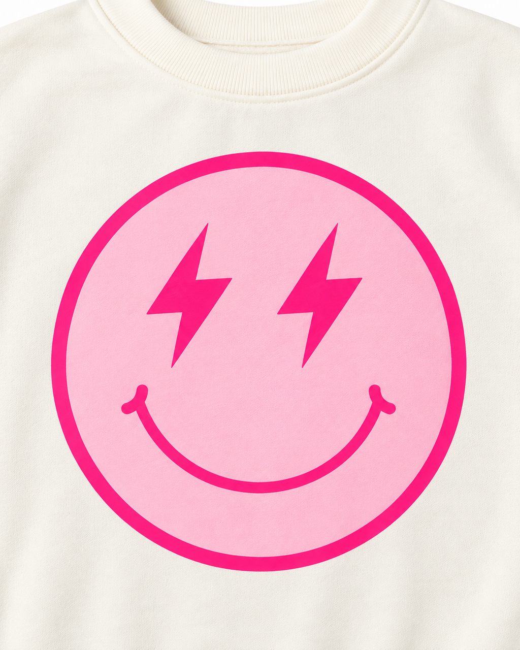Close-up of the light pink smiley face with hot pink lightning-bolt eyes, smile, and circular border on cream fabric
