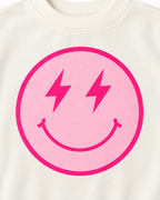 Close-up of the light pink smiley face with hot pink lightning-bolt eyes, smile, and circular border on cream fabric

