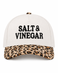 Salt & Vinegar Two-Tone Baseball Cap in Leopard front view showing cream structured cotton crown with bold black embroidered Salt & Vinegar block lettering, tan and brown leopard print bill, and leopard print top button on white background
