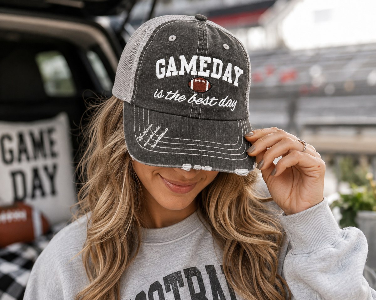 Woman wearing Gameday Is the Best Day distressed charcoal trucker hat at a tailgate
