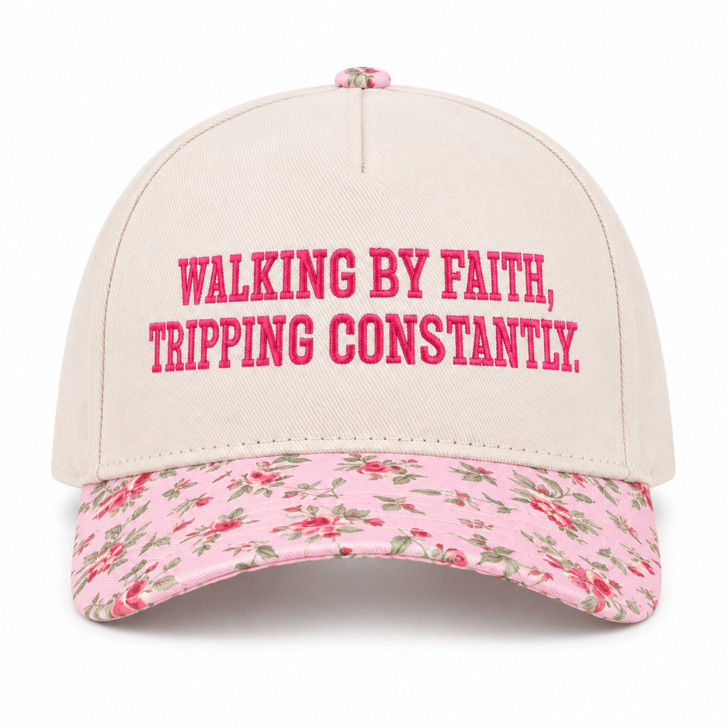 Walking By Faith Tripping Constantly Baseball Cap in Floral front view showing cream cotton crown with hot pink embroidered Walking By Faith Tripping Constantly block lettering, pink floral bill with red roses and green leaves, and pink floral top button on white background
