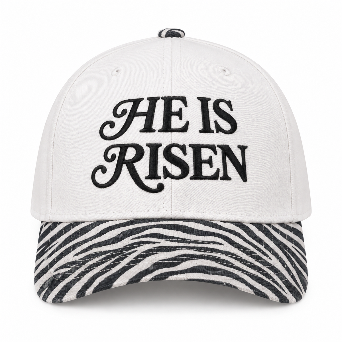 He Is Risen Baseball Cap in Zebra front view showing white cotton crown with black decorative script He Is Risen embroidery, black and white zebra print bill, and zebra print top button on white background
